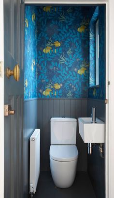 a toilet and sink in a small room with blue wallpaper on the walls behind it