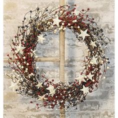 a wreath with stars and berries hanging on a brick wall next to a wooden cross