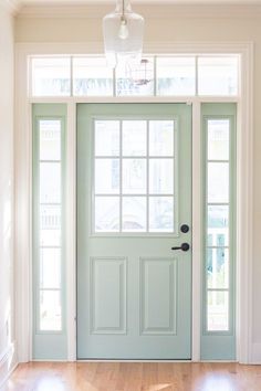 the front door is painted light blue and has two glass panels on each side, along with wood floors