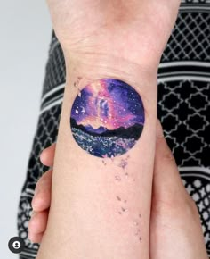 a person with a tattoo on their arm that has an image of the sky and stars