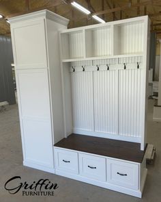 an empty room with some white cabinets and drawers on it's sides, in front of a wall mounted coat rack