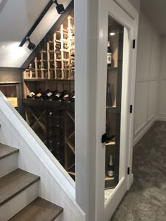 a wine cellar in the corner of a room with stairs leading up to an upper level