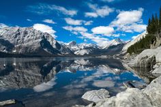 the mountains are reflected in the still water on the lake's edge, while clouds loom overhead