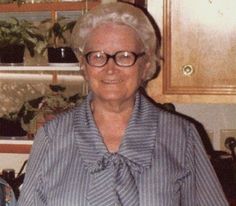 an older woman wearing glasses standing in a kitchen