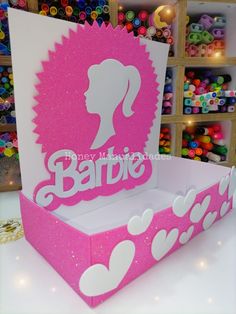 a pink and white cardboard box with the word barbie on it's side, decorated with hearts