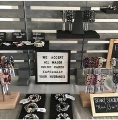 several bracelets and necklaces are on display in a store with signs that say we accept all major credit cards especially your husbands