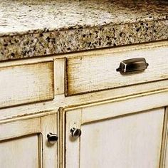 an old white kitchen cabinet with granite counter tops and drawer pulls on the bottom drawers