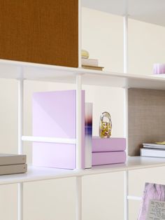 a shelf filled with books and other items on top of white shelving unit units