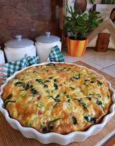 a quiche with spinach and cheese in a white dish on a wooden table