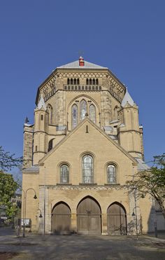 an old church with two large doors and a steeple on the top, surrounded by trees