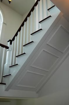 an open staircase leading up to the second floor with white painted walls and wood handrails