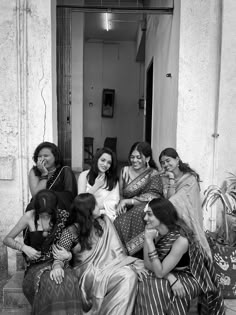 a group of women sitting on top of each other in front of a doorway together