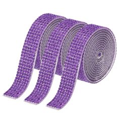 four rolls of purple sequinized ribbon on white background