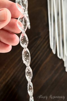 a hand holding a glass bead on top of a wooden table