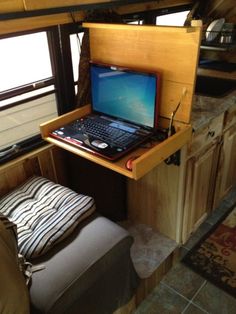 a laptop computer sitting on top of a wooden desk next to a chair and window