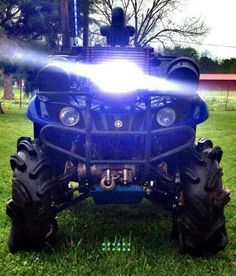 a four - wheeler with its lights on is parked in the grass