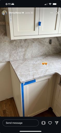 a kitchen counter with blue tape on it and white cabinets in the backround