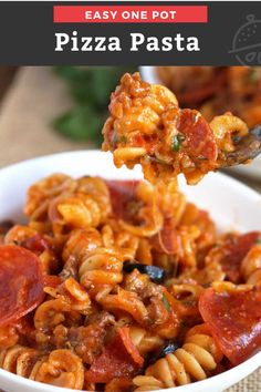 a spoon full of pasta with pepperoni and cheese on it, in a white bowl