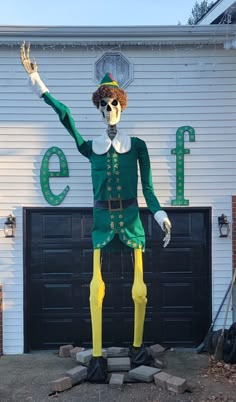 a statue of a man dressed in green and yellow is standing on the side of a building