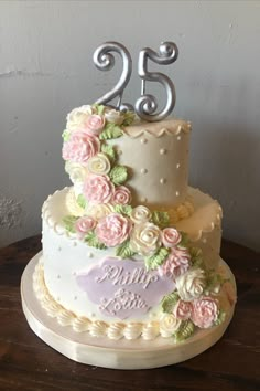 a wedding cake decorated with flowers and the number twenty five on it's side