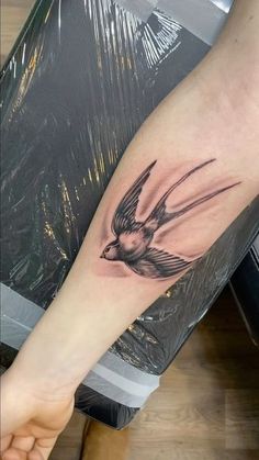 a small bird tattoo on the right arm