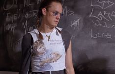 a man standing in front of a chalkboard with writing on it and wearing glasses