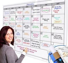 a woman standing next to a dry erase calendar