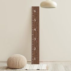 a wooden growth chart next to a white ball on the floor with a lamp above it