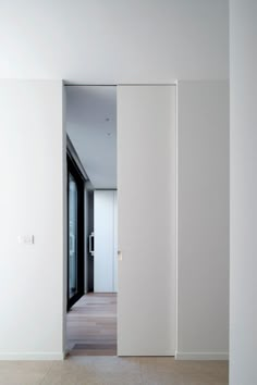 an empty room with white walls and wood flooring is seen through the open door