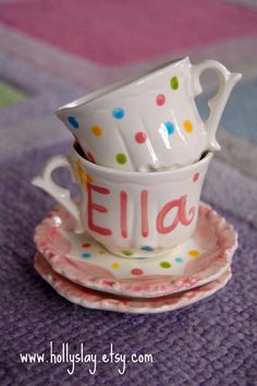 two cups and saucers with the word ella on them are sitting on a plate