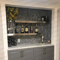 a kitchen with grey cabinets and shelves filled with liquor bottles on top of it's backsplash