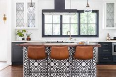 two brown leather stools sit at the center of a kitchen island in front of an oven