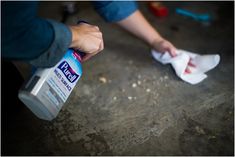 a person is cleaning their feet with a disinfectant bottle and cloth on the floor