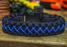 a black and blue braided bracelet sitting on top of a wooden table next to money