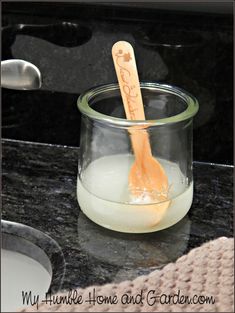 a wooden spoon sticking out of a jar filled with liquid on top of a counter