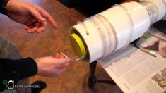 two people are pouring olives into a large glass jar that is on top of a table