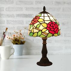 a stained glass lamp sitting on top of a table next to a vase with flowers