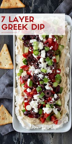 a platter filled with greek dip and pita bread, topped with olives