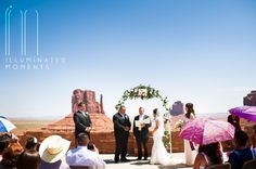 a couple getting married under an arch at their wedding ceremony in monument park, utah