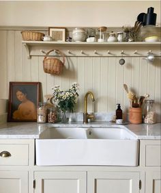 a white kitchen sink sitting under a window next to a shelf filled with pots and pans