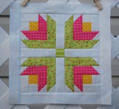 a close up of a quilt on a fence with some clothes pins attached to it