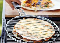 a person cooking food on top of a bbq with a pizza in the background