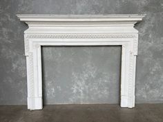 an old white fireplace in a room with gray walls