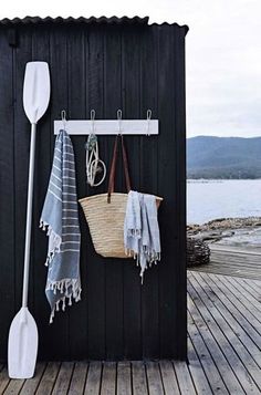 a black shed with two white paddles hanging from it's side and towels on the hooks