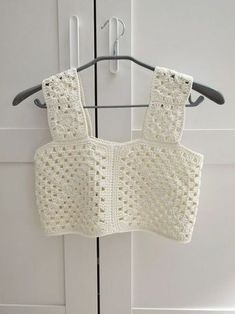 a crocheted sweater hanging on a hook in front of a white cabinet door