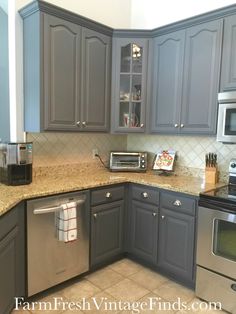 a kitchen with gray cabinets and granite counter tops, stainless steel appliances and an oven