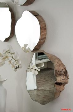 three mirrors mounted to the side of a wall next to a vase with flowers on it