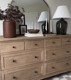 a dresser with a mirror, lamp and vase on top