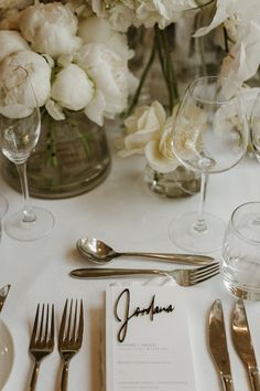 the table is set with silverware and white flowers