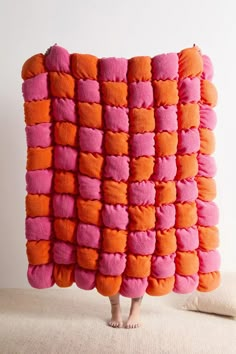 a person standing in front of an orange and pink blanket that is made to look like squares